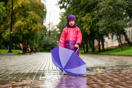 Child with an umbrella walks in the rain. Little boy with umbrella outdoors.