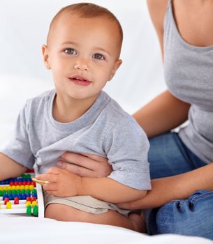 Fascinated about his world. A curious little toddler looking at the camera and holding an abacus