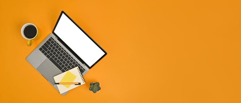 Mock up laptop computer with blank screen, notepad and coffee cup on yellow background. Copy space for your advertise text.