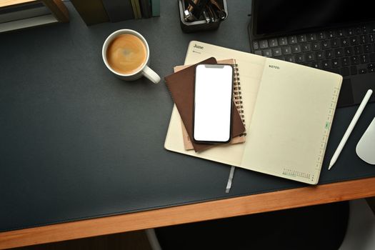 Modern workplace with smart phone, notepad, laptop and coffee cup on black leather.