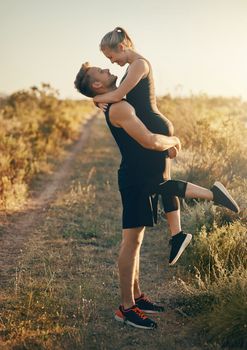 He lifts me up when there are no weights around. a young man lifting his girlfriend outdoors