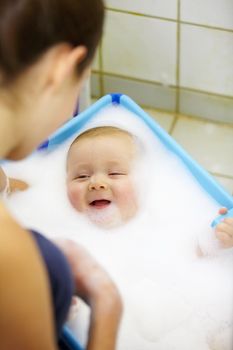 This is fun. Laughing baby boy getting a soapy foam bath from his mom