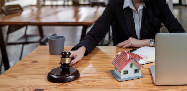 Real Estate Law concept. Gavel on sounding block in hand's female judge at a courtroom, working for the insurance compensations. report the case on table in modern office..