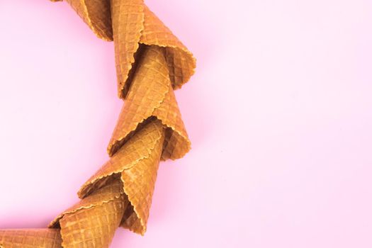smooth circle of waffle cones for ice cream on a pink background.