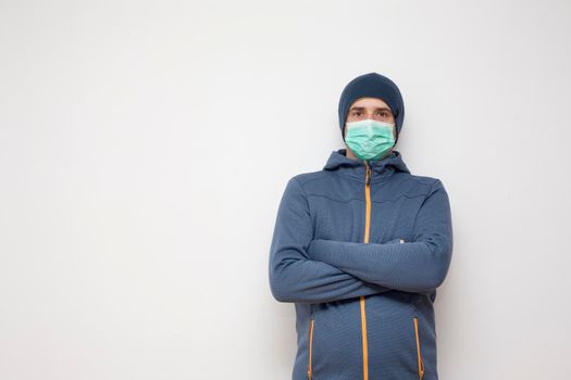Man with green protective mask on white background. A man with a blue jacket, with a hood.