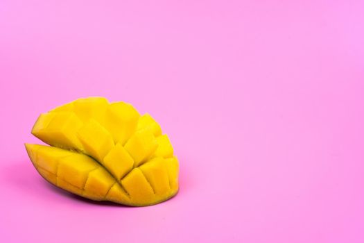 Fresh ripe mango on a pink background. Half a sliced mango on a pink background.