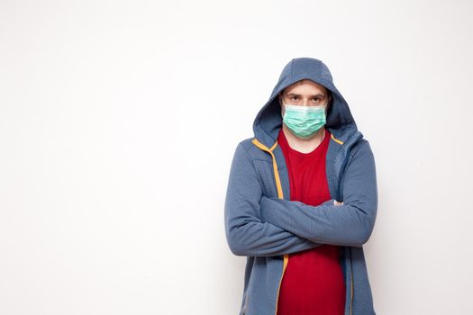 Man with green protective mask on white background. A man with a red sweater and a blue jacket, with a hood.