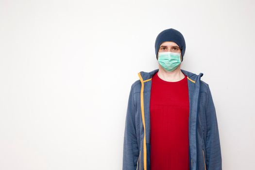 Man with green protective mask on white background. A man with a red sweater and a blue jacket, with a hood.