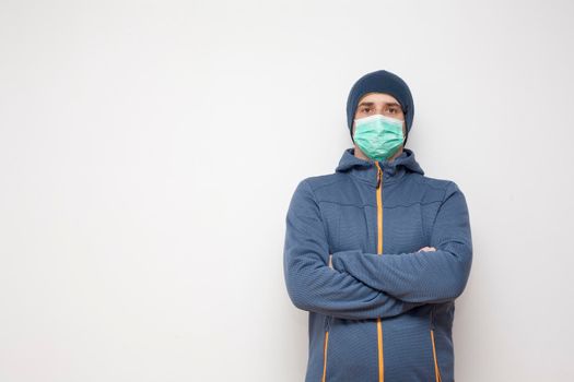 Man with green protective mask on white background. A man with a blue jacket, with a hood.