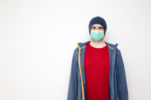 Man with green protective mask on white background. A man with a red sweater and a blue jacket, with a hood.