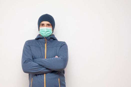 Man with green protective mask on white background. A man with a blue jacket, with a hood.