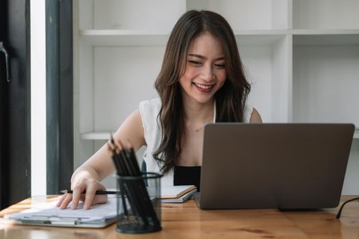 Smilling asian woman using laptop computer for online learning at home. education concept.