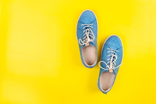 Blue shoes stand on an isolated yellow background.