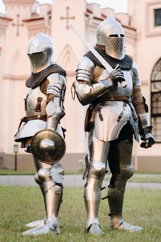 Two knights in armor on the background of a medieval castle.A medieval concept.Metallic texture.