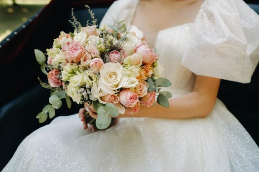 a beautiful wedding bouquet with roses in the hands of the bride.