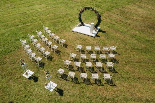 Wedding ceremony on the street on a green lawn with white chairs.