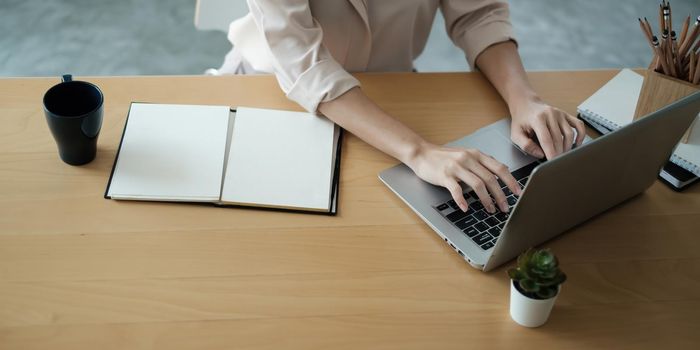 Asian Business woman sitting in office with laptop computer on wooden desk