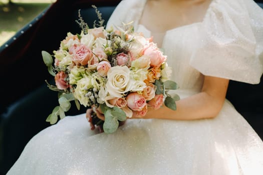 a beautiful wedding bouquet with roses in the hands of the bride.