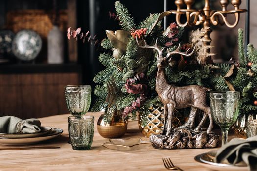 Christmas table decoration, Banquet table with glasses before serving food, Close-up of Christmas dinner table with seasonal decorations, crystal glasses and decorative deer.