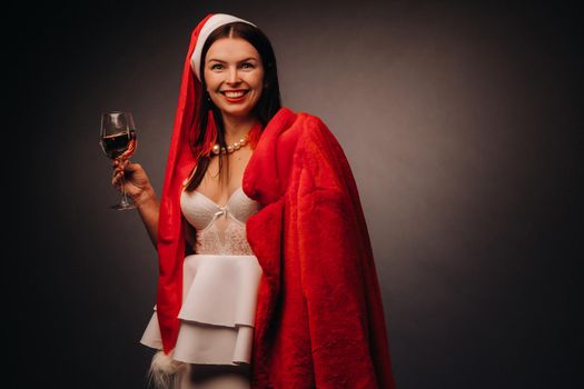 a woman in a Christmas hat and white dress, holding a glass and a red fur coat in her hands, on a black background, Christmas, holiday,