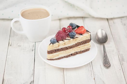 Mix berry colorful slice cake on white plate on wood background