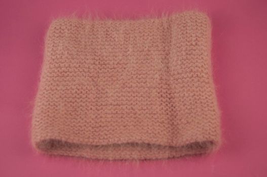 Woman winter knitted scarf front on pink background.