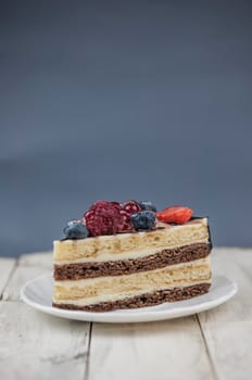 Mix berry slice cake on white plate on wood background