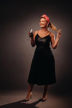 a woman in a black dress holding a glass of champagne on a black background, Christmas, holiday.