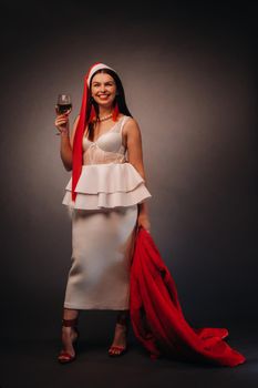 a woman in a Christmas hat and white dress, holding a glass and a red fur coat in her hands, on a black background, Christmas, holiday,