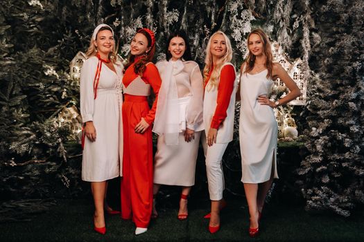 sexy women in festive white and red clothes stand on a Christmas background.