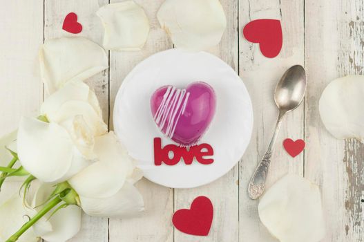 word love and white petals rose with red cake in the shape of a heart is on the table. Romantic date. 