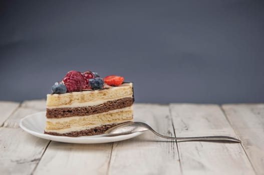 Mix berry slice cake on white plate on wood background