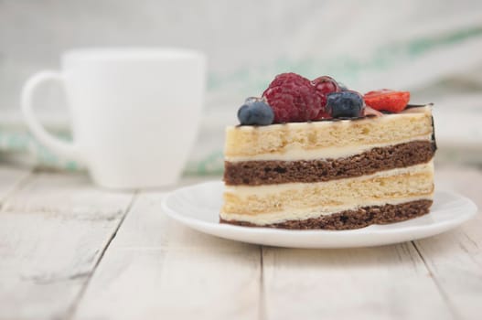 Mix berry colorful slice cake on white plate on wood background