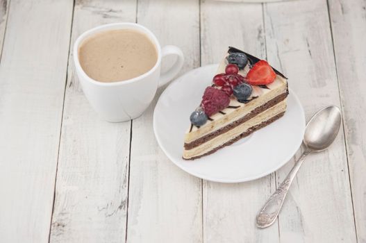 Mix berry colorful slice cake on white plate on wood background