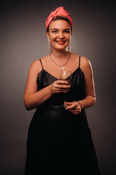 a woman in a black dress holding a glass of champagne on a black background, Christmas, holiday.