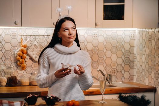 A girl at Christmas stands in the kitchen and holds a cake in her hands and dreams.Woman on new year's eve in the kitchen.