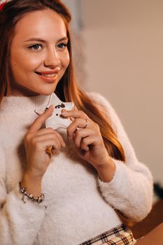 A girl at Christmas holds a cookie in her hands and smiles.Woman on new year's eve in the kitchen