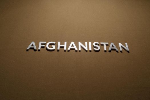 the word afghanistan laid with silver metal letters on rough flat tan khaki canvas fabric surface