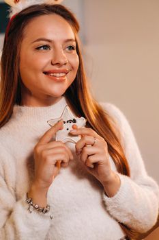 A girl at Christmas holds a cookie in her hands and smiles.Woman on new year's eve in the kitchen