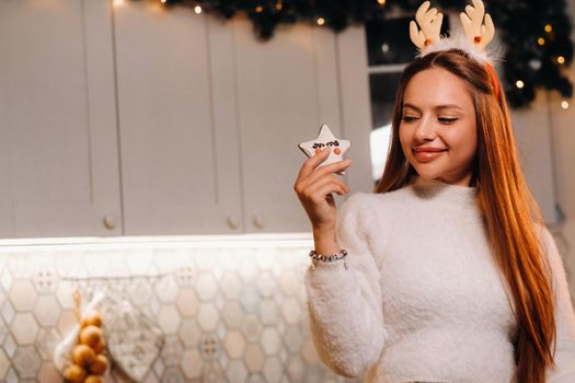 A girl at Christmas holds a cookie in her hands and smiles.Woman on new year's eve in the kitchen