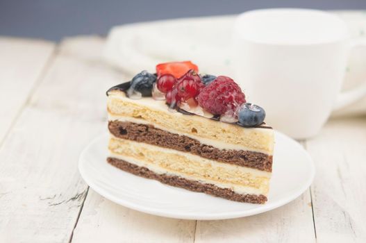 Mix berry colorful slice cake on white plate on wood background