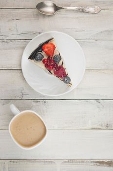 Mix berry colorful slice cake on white plate on wood background