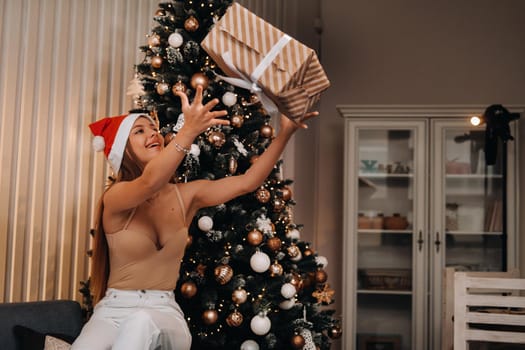 a girl throws a new year's gift on the background of a Christmas tree in the interior.