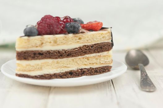 Mix berry colorful slice cake on white plate on wood background