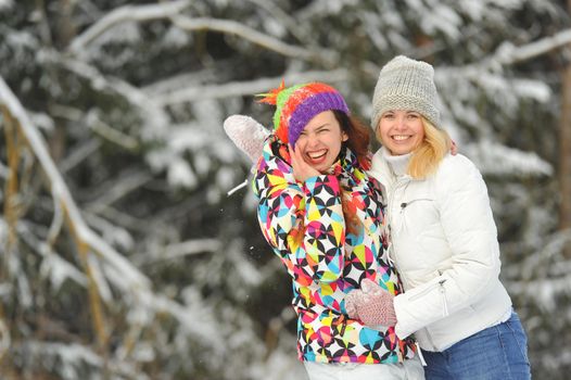 Two girls in the winter forest emotionally hug and smile.Happy women hug and Express joy.