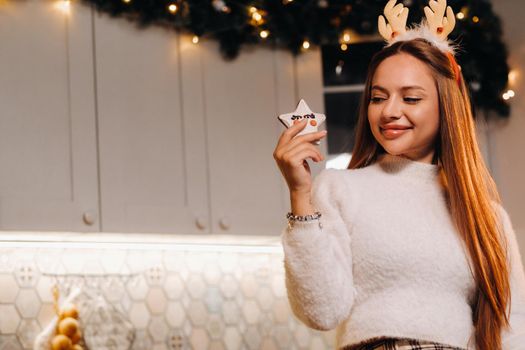 A girl at Christmas holds a cookie in her hands and smiles.Woman on new year's eve in the kitchen