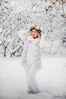 PPortrait of a woman in white clothes in a cold winter forest. Girl with a wreath on her head in a snow-covered winter forest.