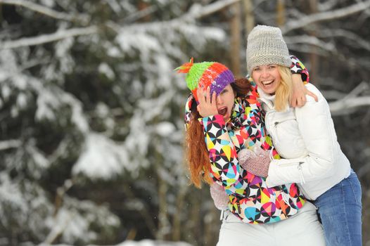 Two girls in the winter forest emotionally hug and smile.Happy women hug and Express joy.