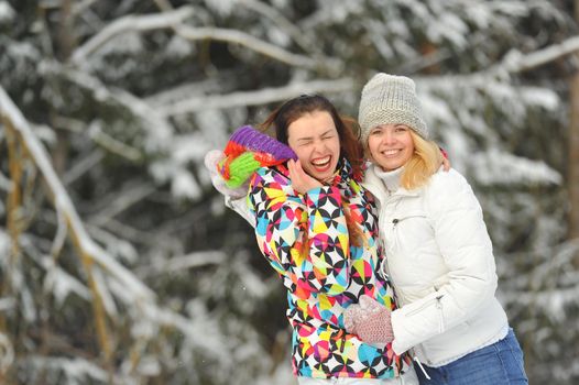 Two girls in the winter forest emotionally hug and smile.Happy women hug and Express joy.