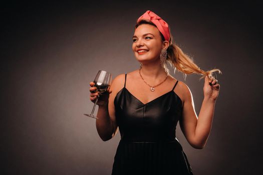 a woman in a black dress holding a glass of champagne on a black background, Christmas, holiday.